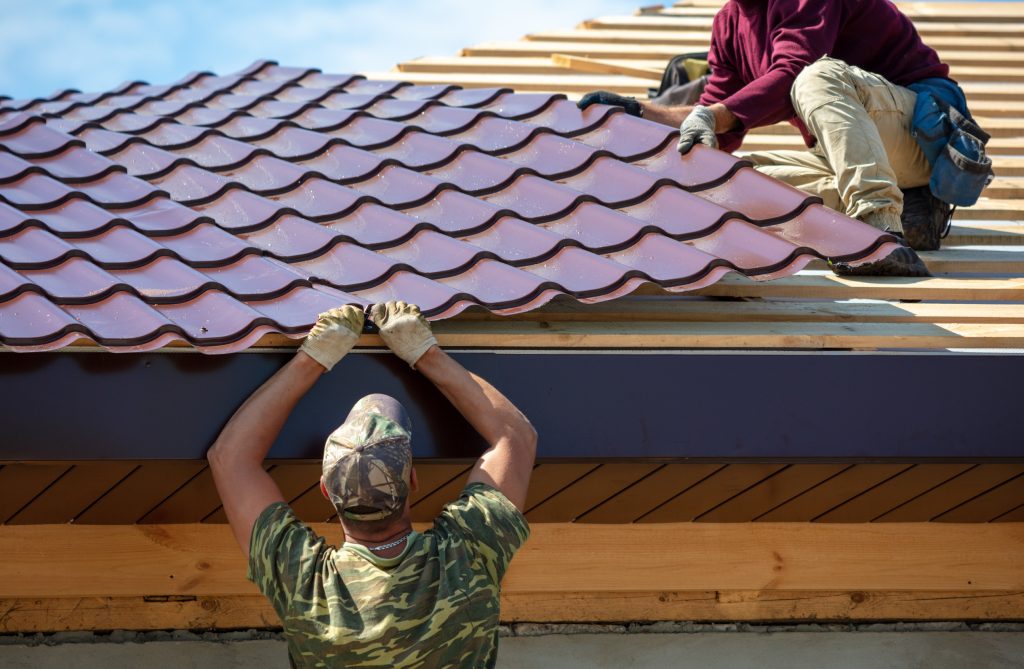 Workers install metal roofing