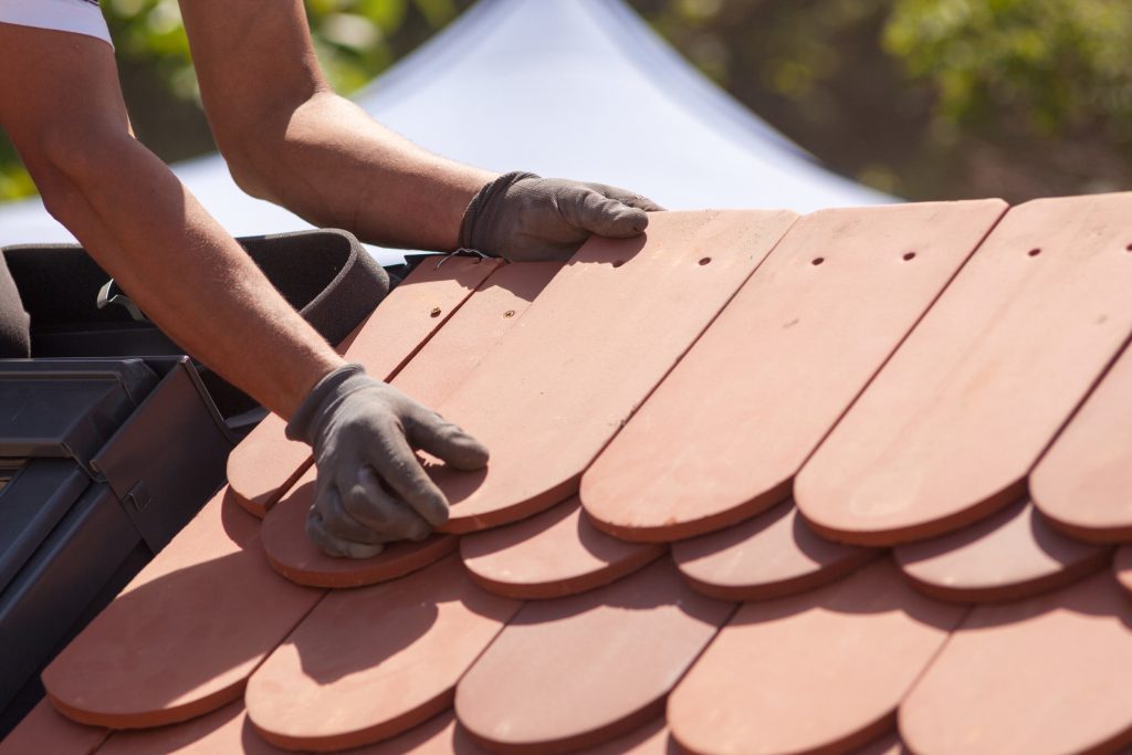Hands of roofer laying tile on the roof